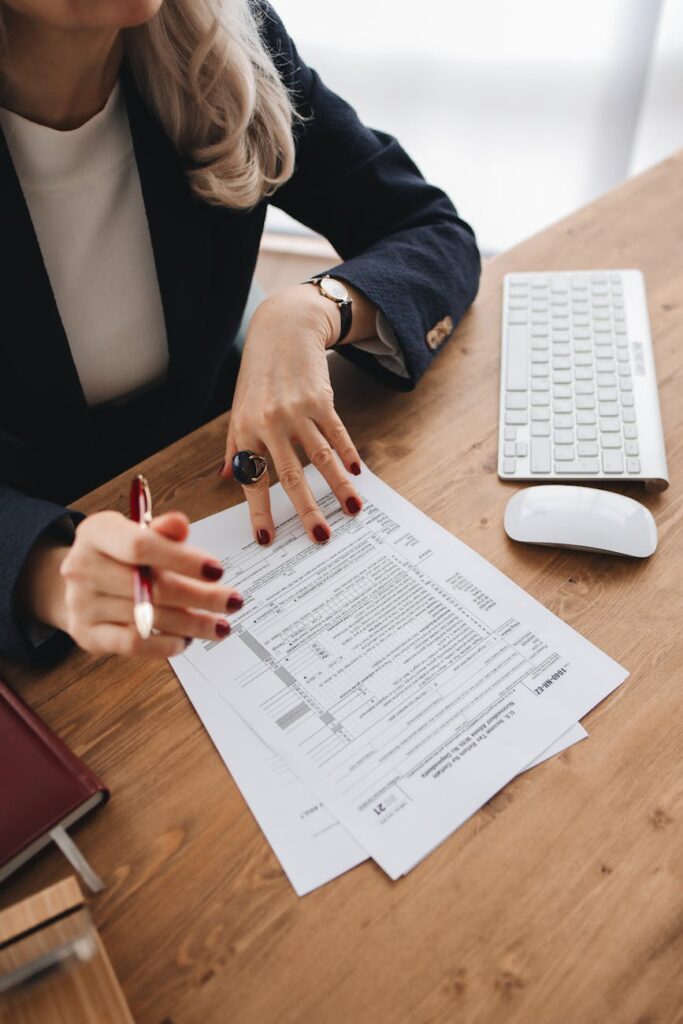 Close-up of a professional examining documents on a wooden desk indoors.